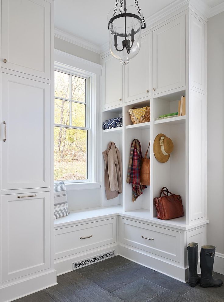 a white closet with several coats and purses hanging on the wall next to it