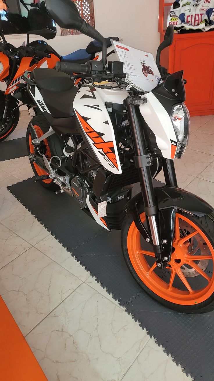 an orange and white motorcycle on display in a showroom