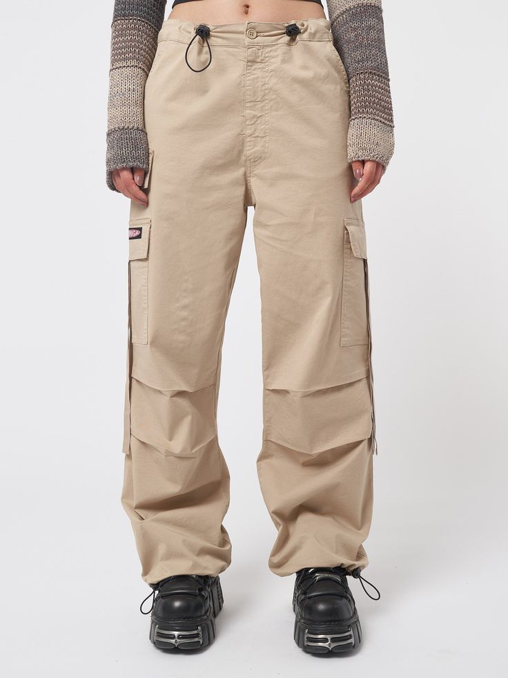 Arm yourself with ’90s and noughties attitude! Take a look at our cargo parachute pants in beige, featuring a baggy fit, utility pockets and adjustable toggle waist and hems. Find y2k pants, retro trousers & more aesthetic clothes at Minga London. Tech Cargo Pants, Jeans With Chains, Retro Trousers, Beige Cargo Pants, 90s Pants, Denim Button Skirt, Minga London, Y2k Pants, Low Rise Flare Jeans