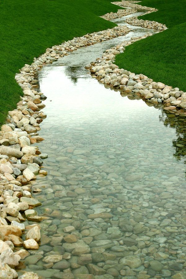 a river running through a lush green field next to a grass covered field with rocks