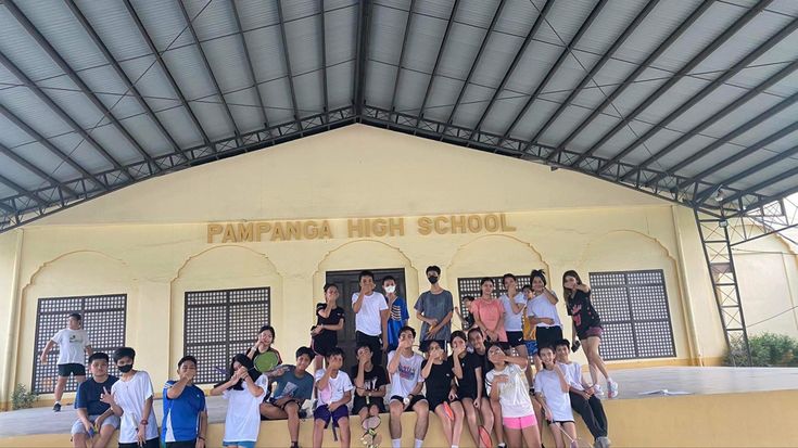 a group of people posing for a photo in front of a school building with the words pamhang high school on it