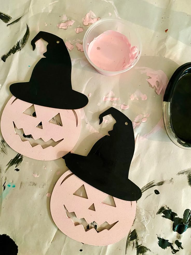 two paper pumpkins sitting on top of a table next to a paint container and brush