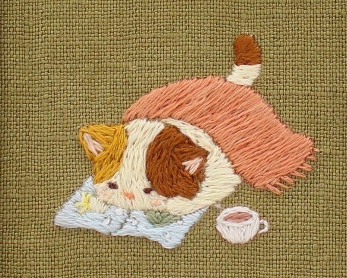 a close up of a piece of cloth with a cat on it and a cup