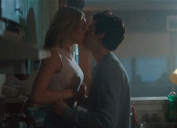 two people standing in a kitchen kissing each other