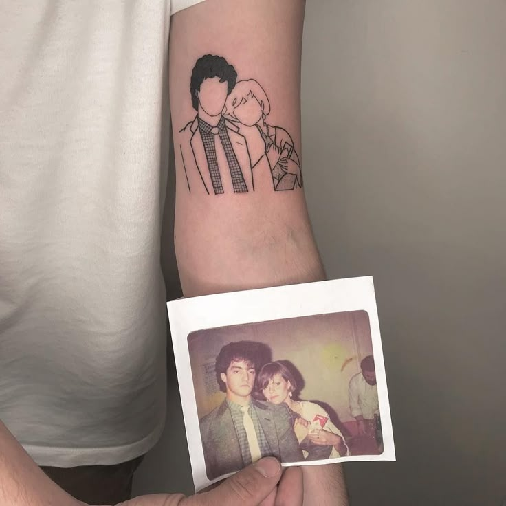 a man with a tattoo on his arm holding up a photo