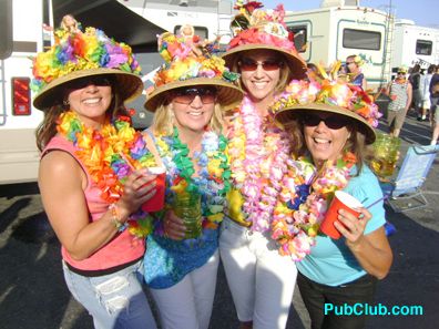 four women wearing colorful hats and leis pose for a photo in front of an rv