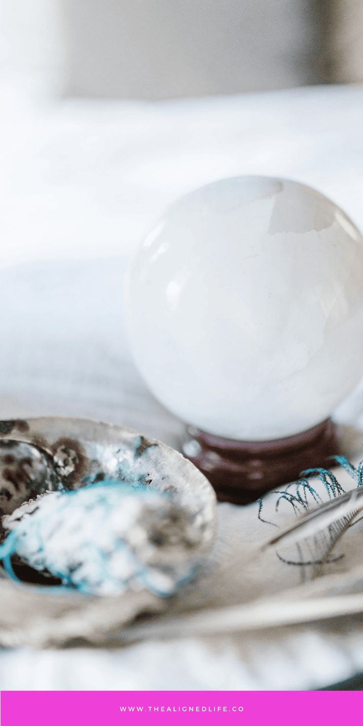 an egg is sitting on a plate next to some spoons and a glass ball