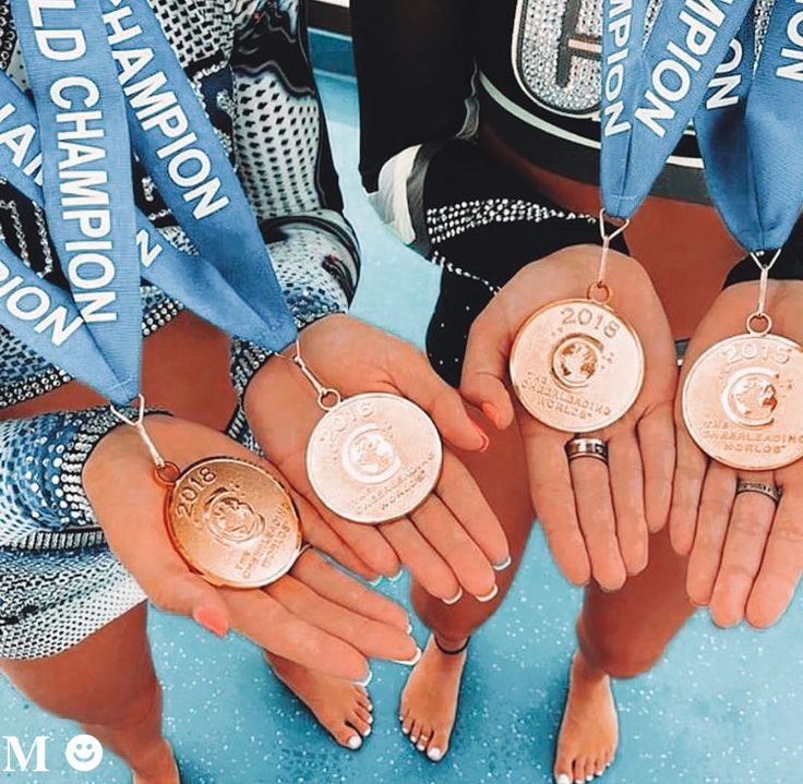 three women holding medals in their hands while standing next to each other on a blue surface