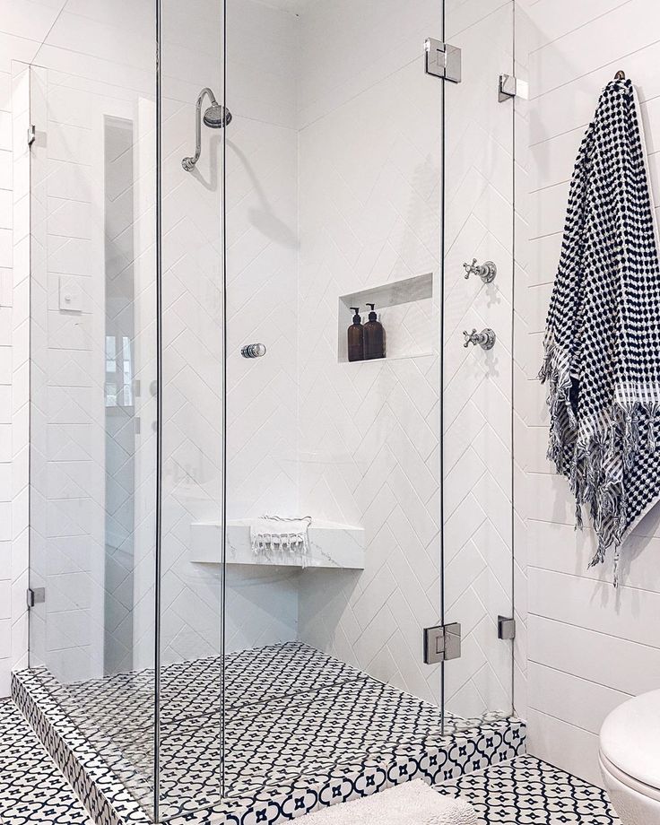 a bathroom with black and white tiles on the floor, shower stall and sink area