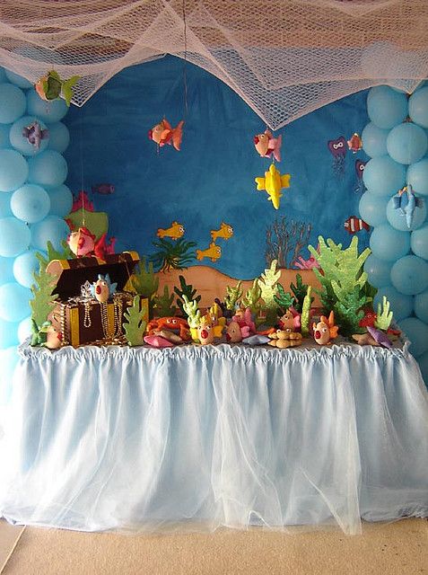 a table topped with lots of balloons under a netted ceiling covered in blue and white