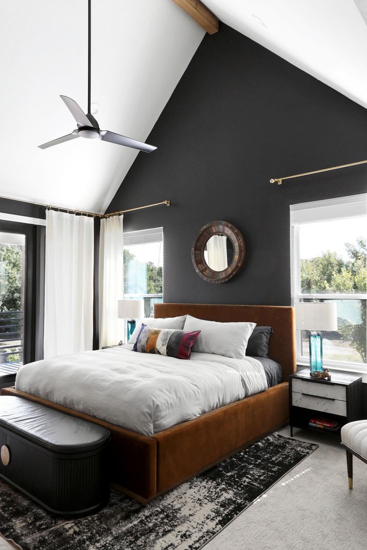 a bedroom with a large bed in the center and two windows on both sides, along with a black accent wall