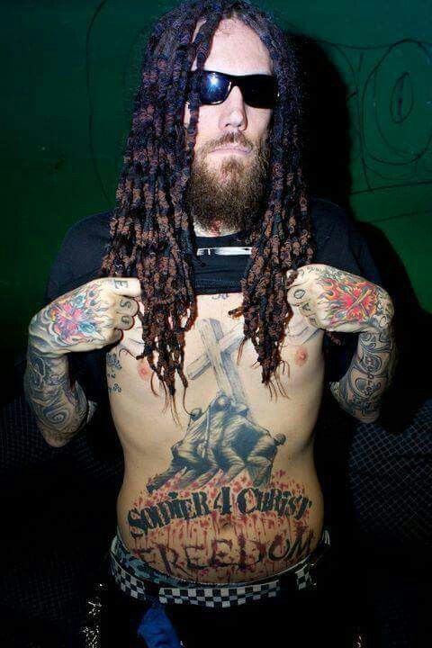 a man with long dreadlocks and tattoos on his chest is posing for the camera