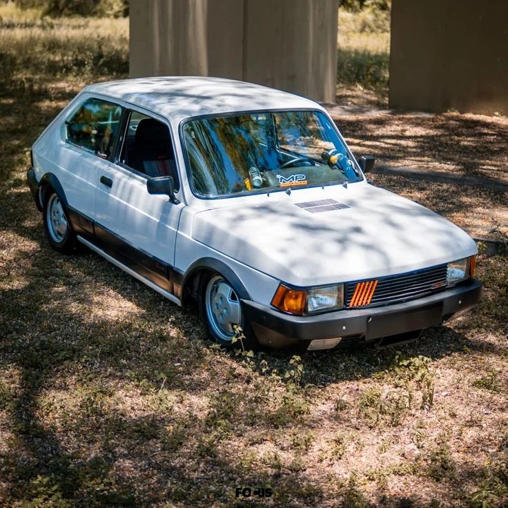 an old white car is parked in the grass