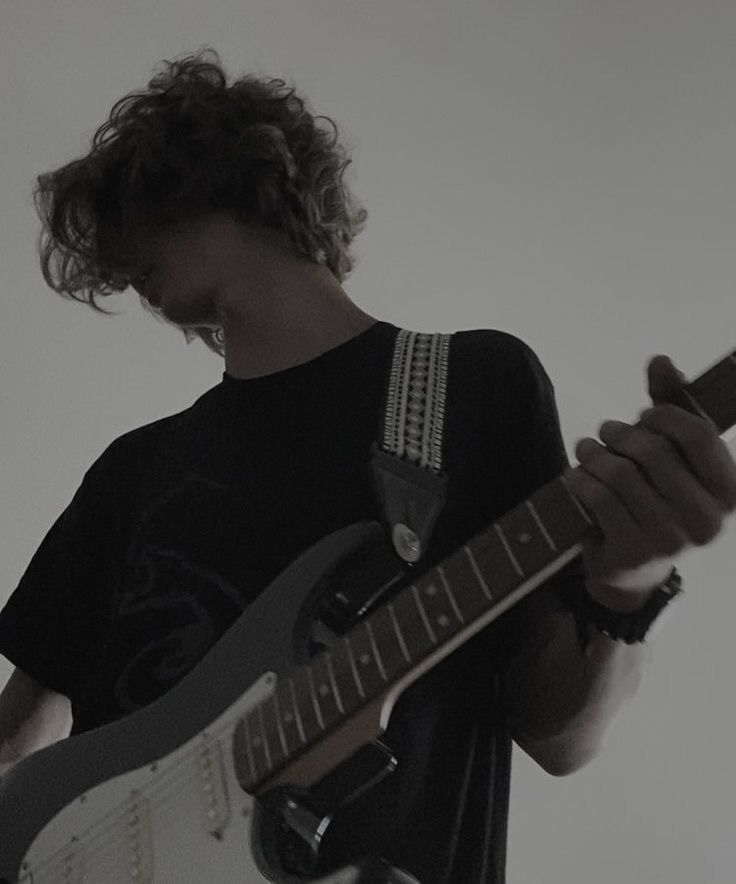 a man with curly hair playing an electric guitar