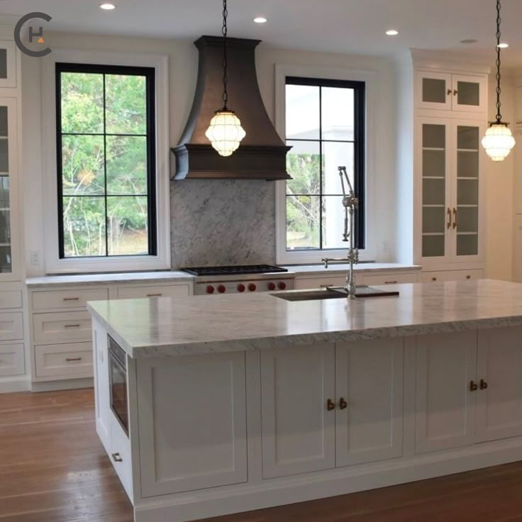 a large kitchen with an island in the middle and two windows on both sides,