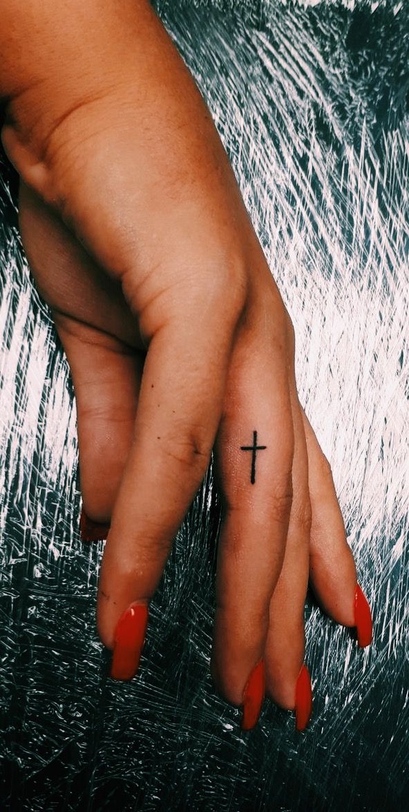 a woman's hand with a cross tattoo on it