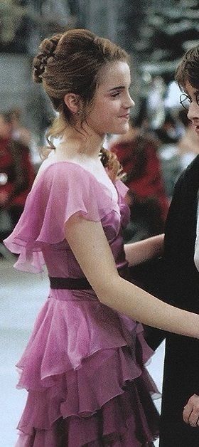 two young women dressed in formal wear, one is holding the other's hand