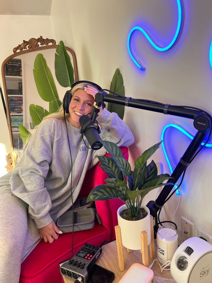 a woman sitting in a red chair with headphones on and a microphone next to her