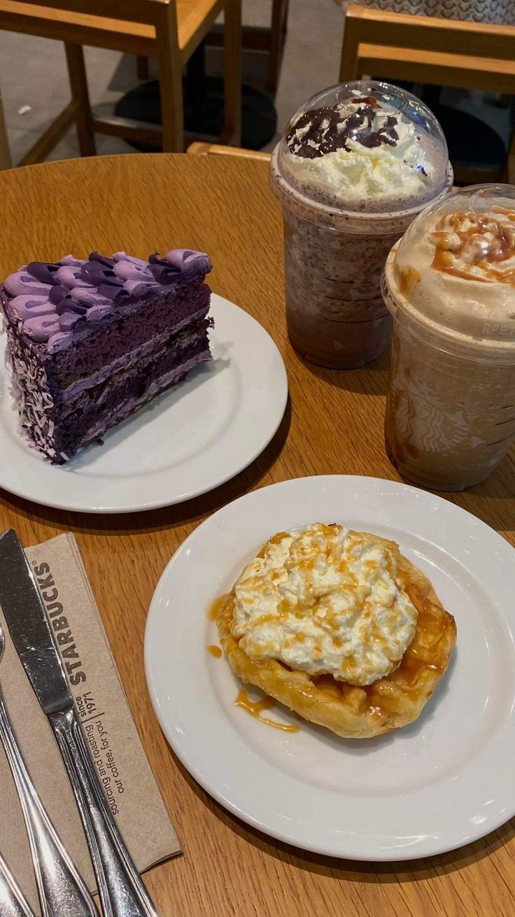 two plates with desserts on them sitting on a table next to cups of coffee