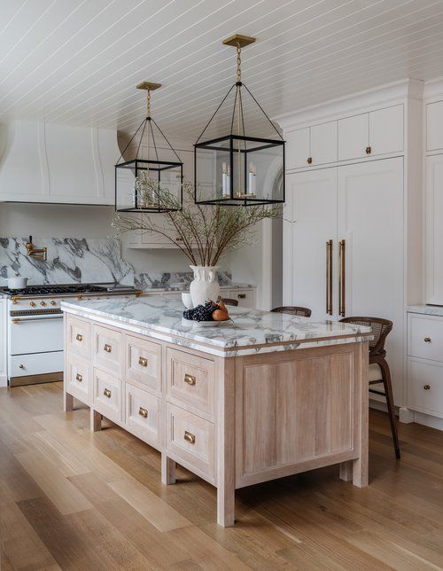 a kitchen with marble counter tops and wooden cabinets in the center, along with an island