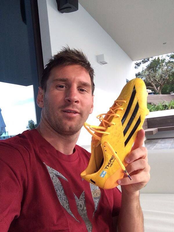 a man holding up a yellow soccer shoe