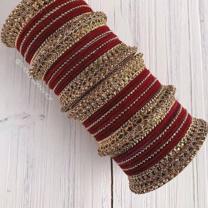 a stack of red and gold bracelets sitting on top of a white wooden floor