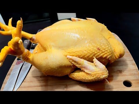 a large yellow chicken sitting on top of a wooden cutting board next to a knife