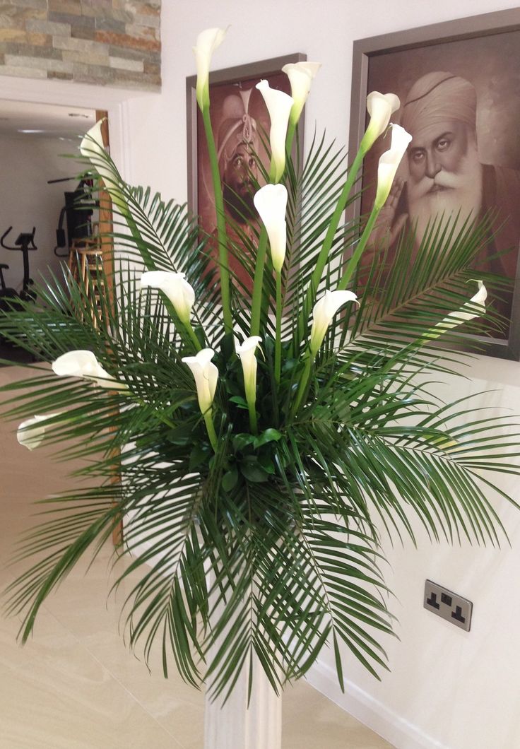 a vase filled with white flowers sitting on top of a table next to two framed pictures