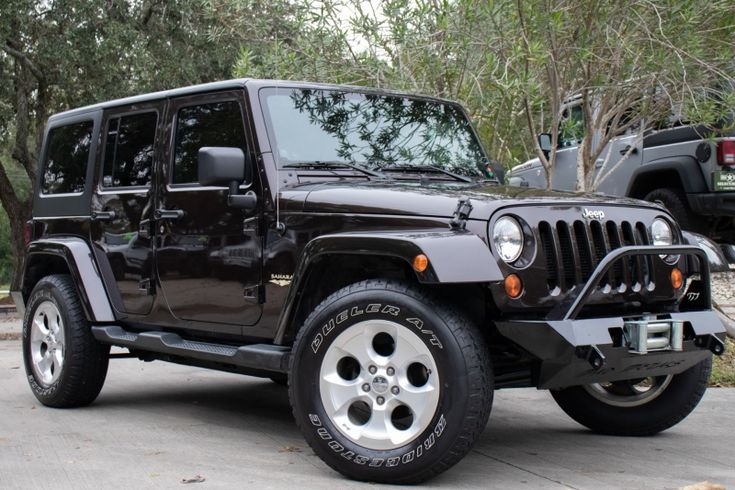 a black jeep is parked in front of some trees