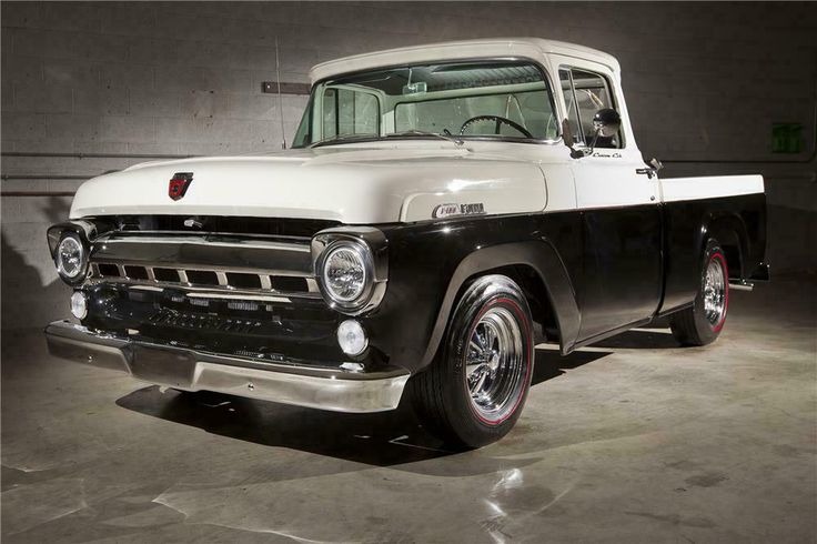 an old black and white pickup truck parked in a garage with no one around it