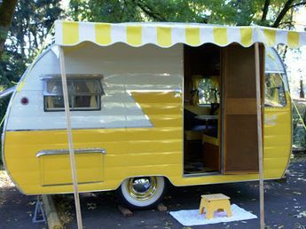 a yellow and white camper parked on the side of a road next to trees