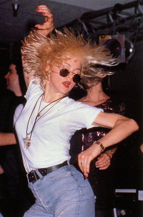 a woman dancing with her hair in the air and sunglasses on top of her head