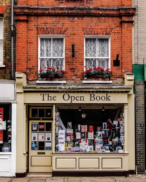 an open book store on the corner of a street in front of some brick buildings