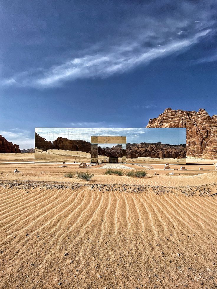 two mirrors are in the middle of an empty desert area with rocks and grass on either side