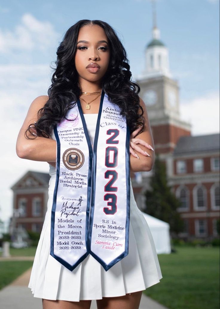 a woman in a white dress is posing for the camera with her graduation sash around her neck