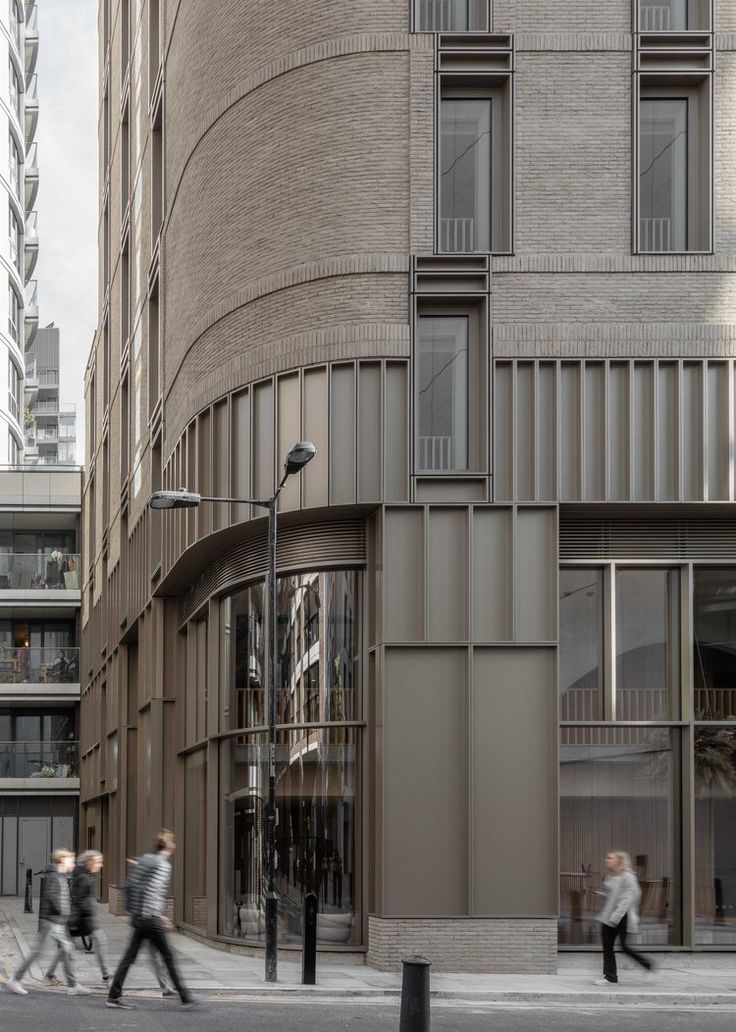 people walking on the sidewalk in front of a building