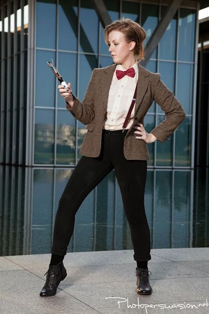 a woman in a suit and bow tie holding a cell phone