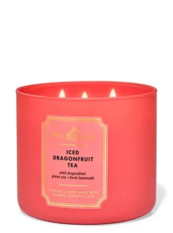 a pink candle with three lit candles in it and the words iced dragonfruit tea on