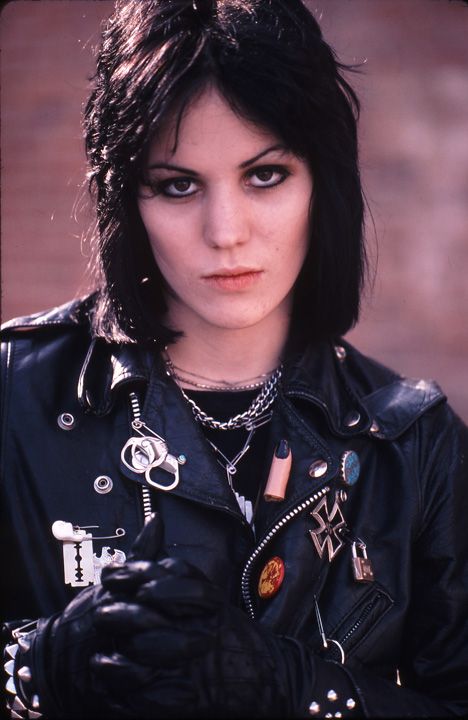 a woman with black hair and piercings wearing a leather jacket is posing for the camera