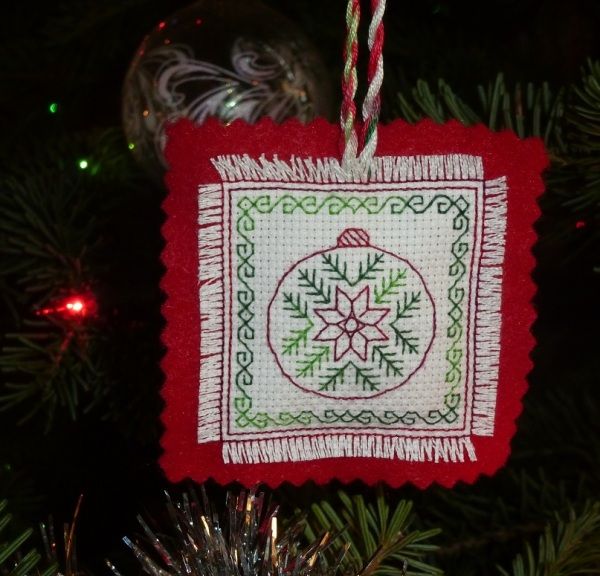 a cross stitch ornament hanging from a christmas tree