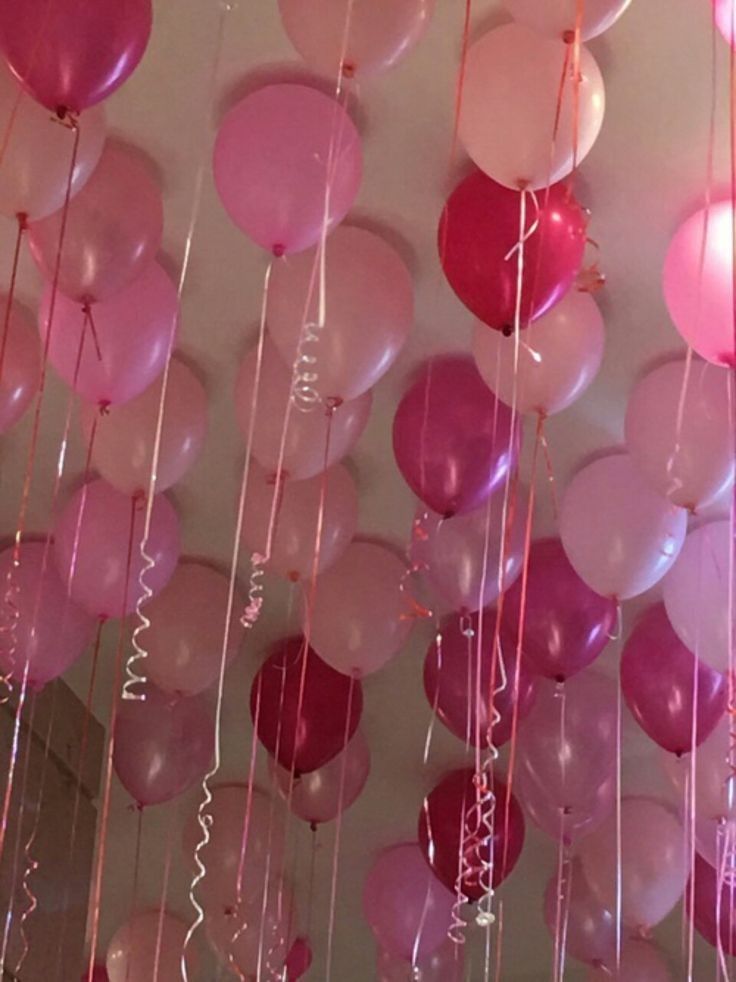 many pink and white balloons hanging from the ceiling