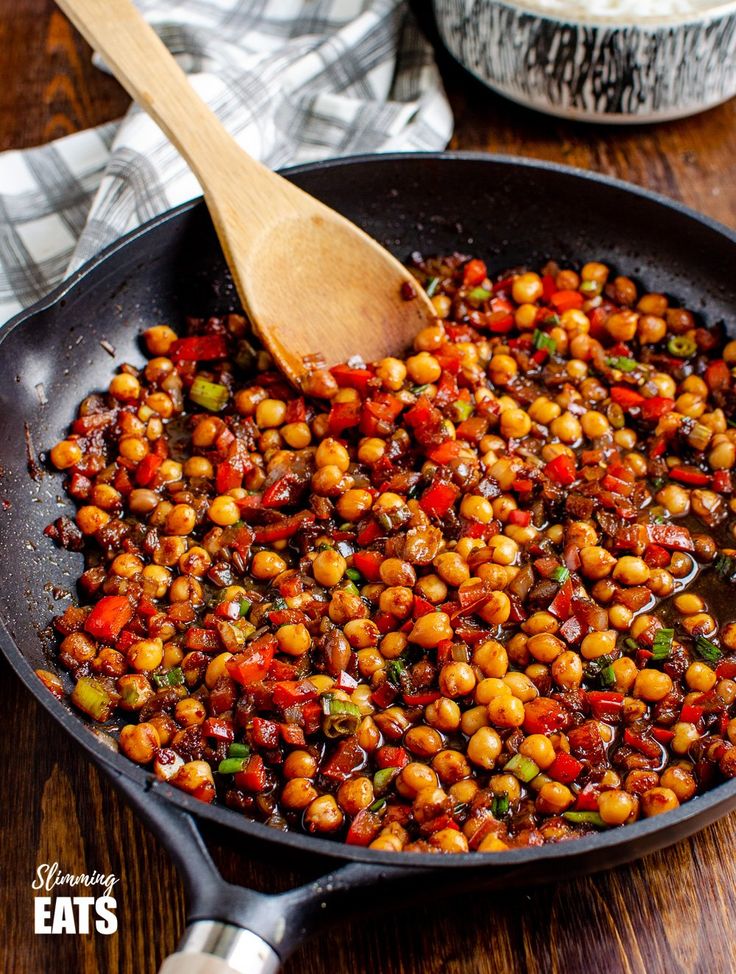 a skillet filled with cooked beans on top of a wooden table