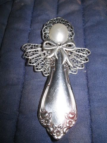 a silver angel brooch sitting on top of a blue cloth