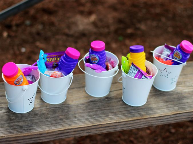 several buckets filled with different colored items on top of a wooden bench in the park