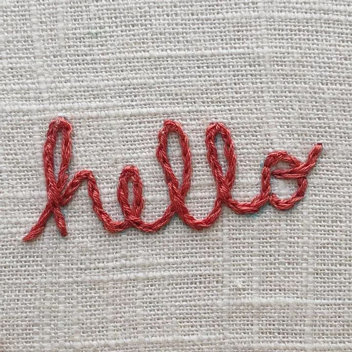 the word hello written in red thread on a white cloth