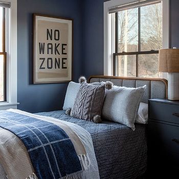 a bedroom with blue walls and two windows