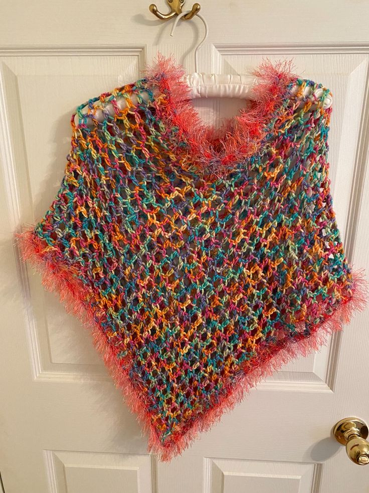 Add a touch of bohemian style to your little girl's outfit with this beautiful handmade poncho shawl. The pink and multi color and fringe accents give it a playful and fun look that is perfect for travel or casual occasions. The round neckline and pullover closure make it easy to wear and comfortable for all-day wear. Made with care in the United States, this sweater is a one-of-a-kind piece that your little girl will love. The crochet fabric type adds texture and interest to the garment, while the vintage style gives it a unique touch. It measure 25 inches wide and 22 inches in length. The head opening is 24 inches. Perfect for girls of all ages, this cape-style sweater is a must-have addition to any wardrobe. Pink Bohemian Poncho For Spring, Spring Bohemian Pink Poncho, Multicolor Beach Shawl For Spring, Spring Beach Shawl In Multicolor, One Size Bohemian Pink Poncho, Multicolor Shawl Poncho For Festival, Multicolor Hippie Shawl Poncho, Hippie Multicolor Shawl Poncho, Multicolor One-size Festival Poncho