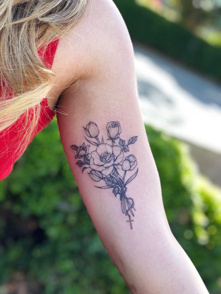 a woman with a tattoo on her arm holding a bouquet of flowers in her left arm