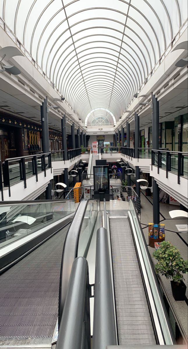 an empty shopping mall with escalators and benches