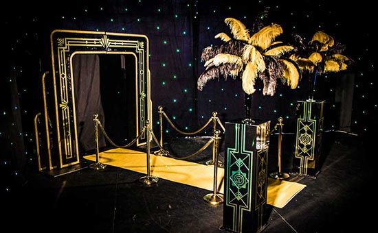 a stage set up for an event with palm trees in the middle and black backdrop